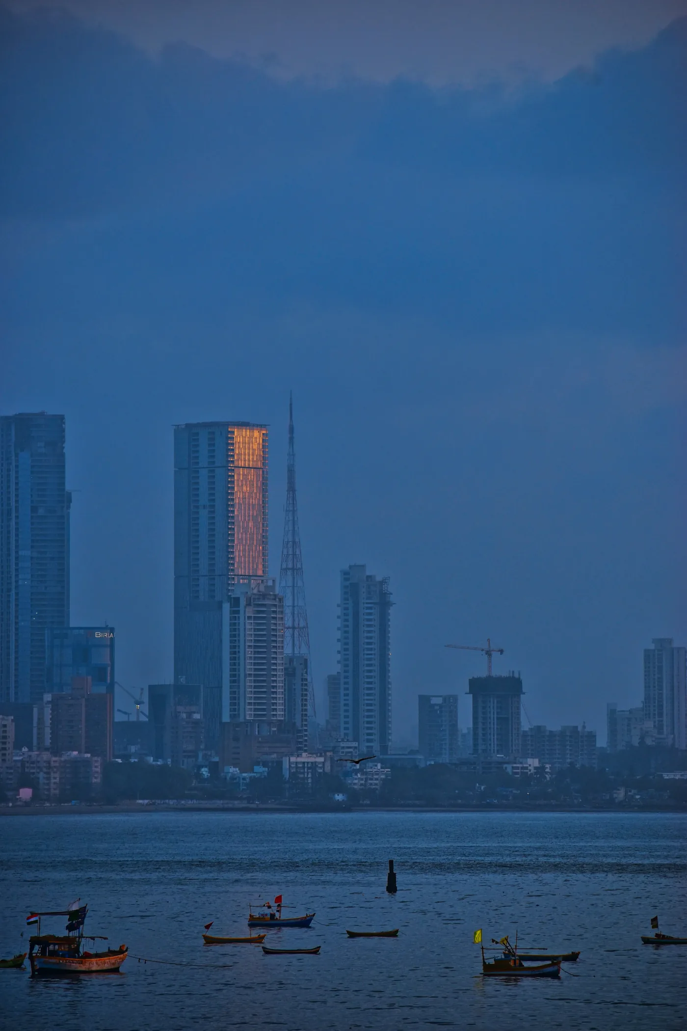 The bay at dusk — fishing boats at anchor below the Worli skyline, one tower still catching the last of the light.